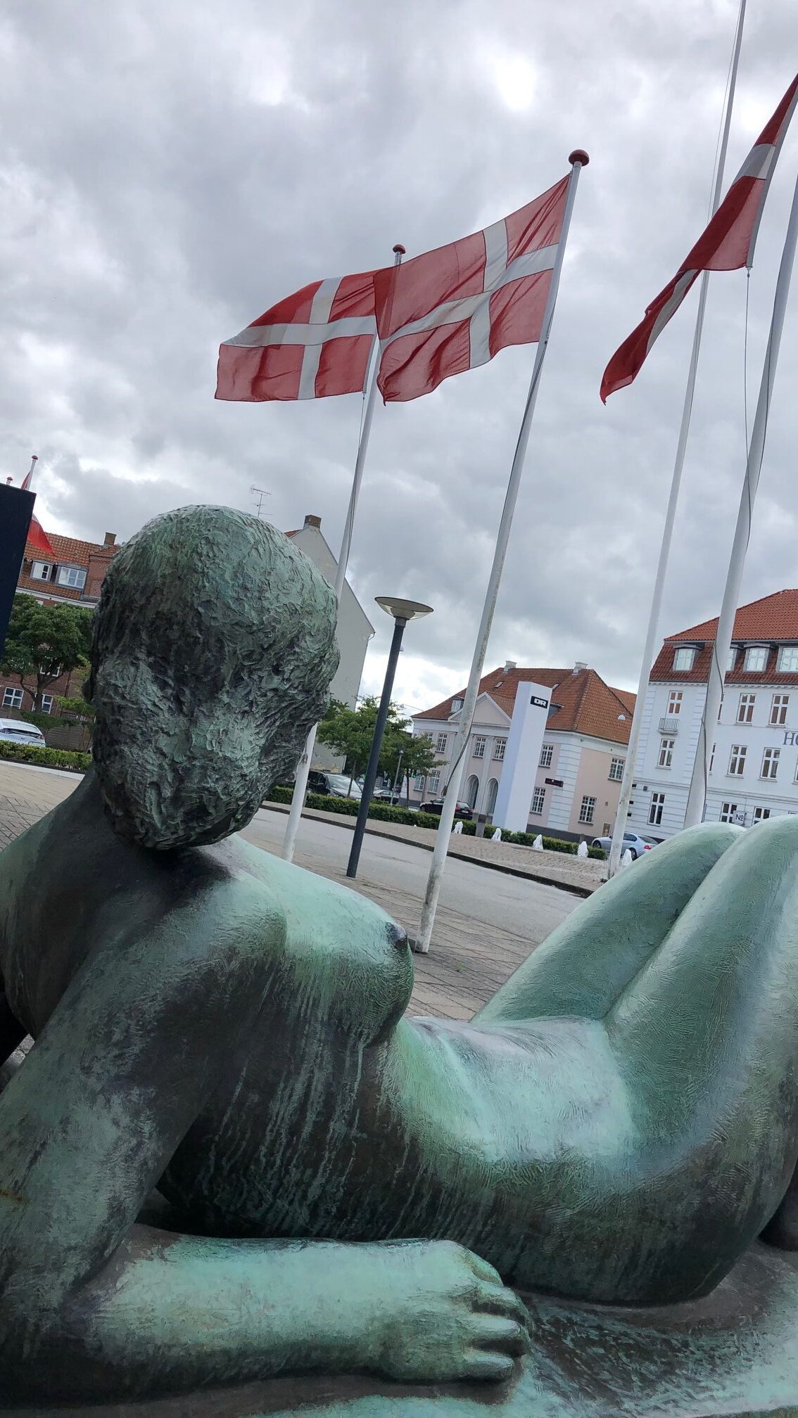 Skulptur einer liegenden Frau vor dänischen Flaggen