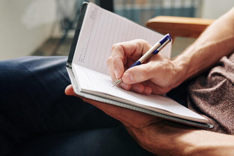 Close-up image of man enjoying moment for himself and filling diary after difficult day